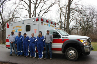 Six members of the Reily Township EMS squad stand in front of a Reily Township ambulance. 
